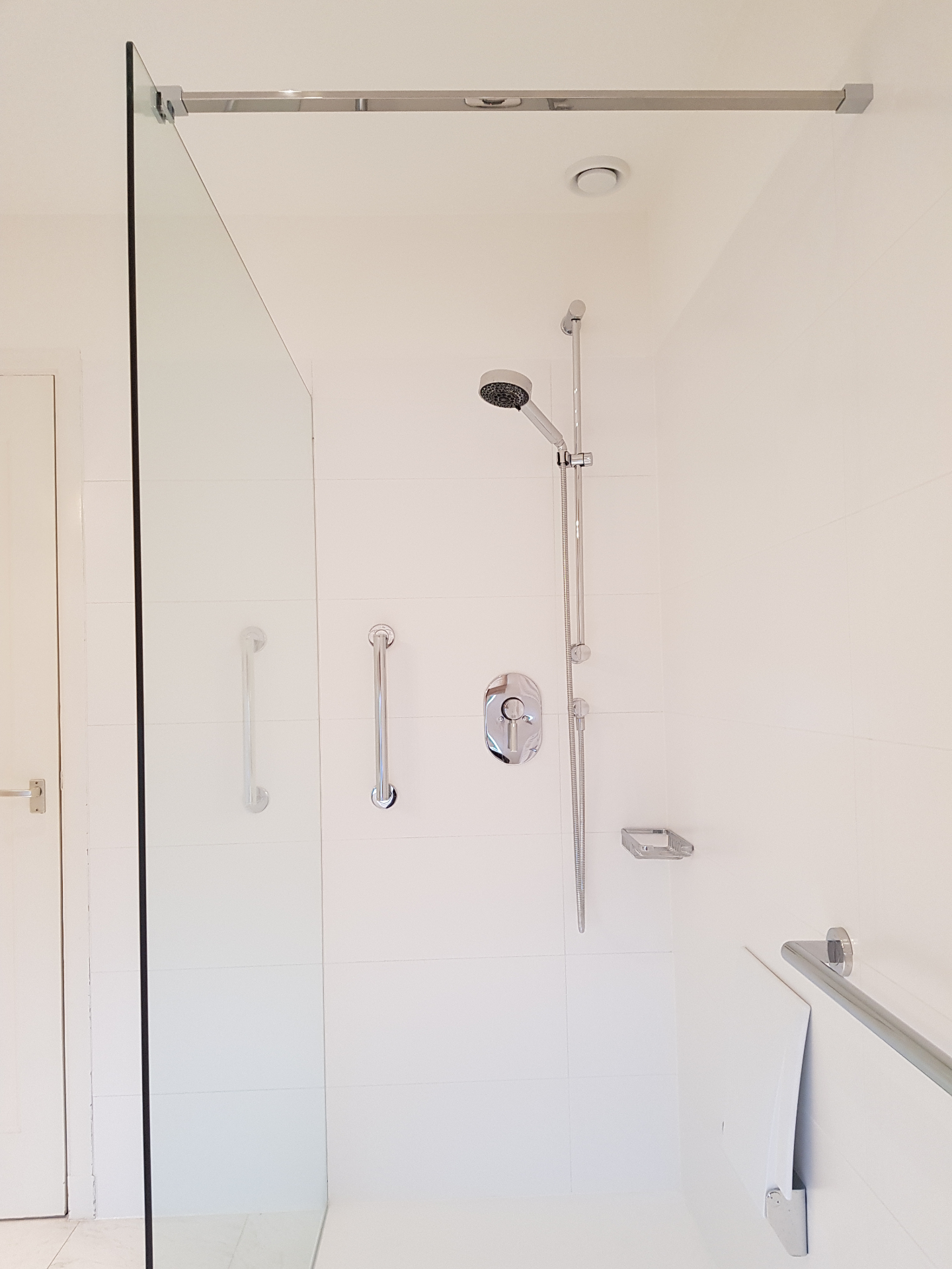 Witte inloopdouche met glaswand en zilveren handgrepen